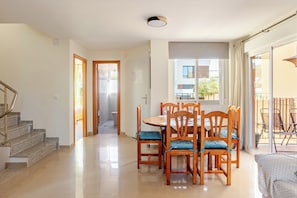Un vaste espace de vie comprenant une table à manger, des chaises, un escalier et une vue sur l’extérieur.