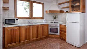 A kitchen with wooden cabinets, a microwave, a stove, and a refrigerator. - Dolac Green Side Apartments (Jelsa)
