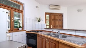A kitchen with wooden cabinets, a stainless steel sink, a stove, and a dishwasher. - Dolac Green Side Apartments (Jelsa)