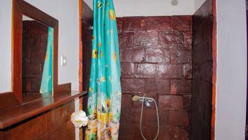 Une salle de bain avec un banc en bois, une douche avec un tuyau en métal et un miroir au-dessus du banc.