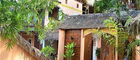 Un bâtiment traditionnel avec un toit de chaume, entouré d’une végétation luxuriante et de bambous.