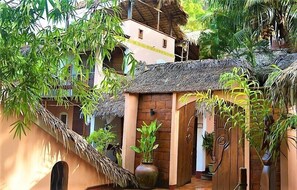 Un edificio tradizionale con tetto di paglia, immerso nel verde e circondato da bambù.
