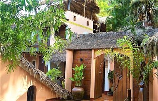 Un edificio tradicional con techo de paja, rodeado de abundante vegetación y bambú.