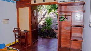 A wooden room with a door leading to a garden, a chair, a small table, and a shelf with hooks. - Hotel Restaurant Les Boucaniers (Nosy Be)