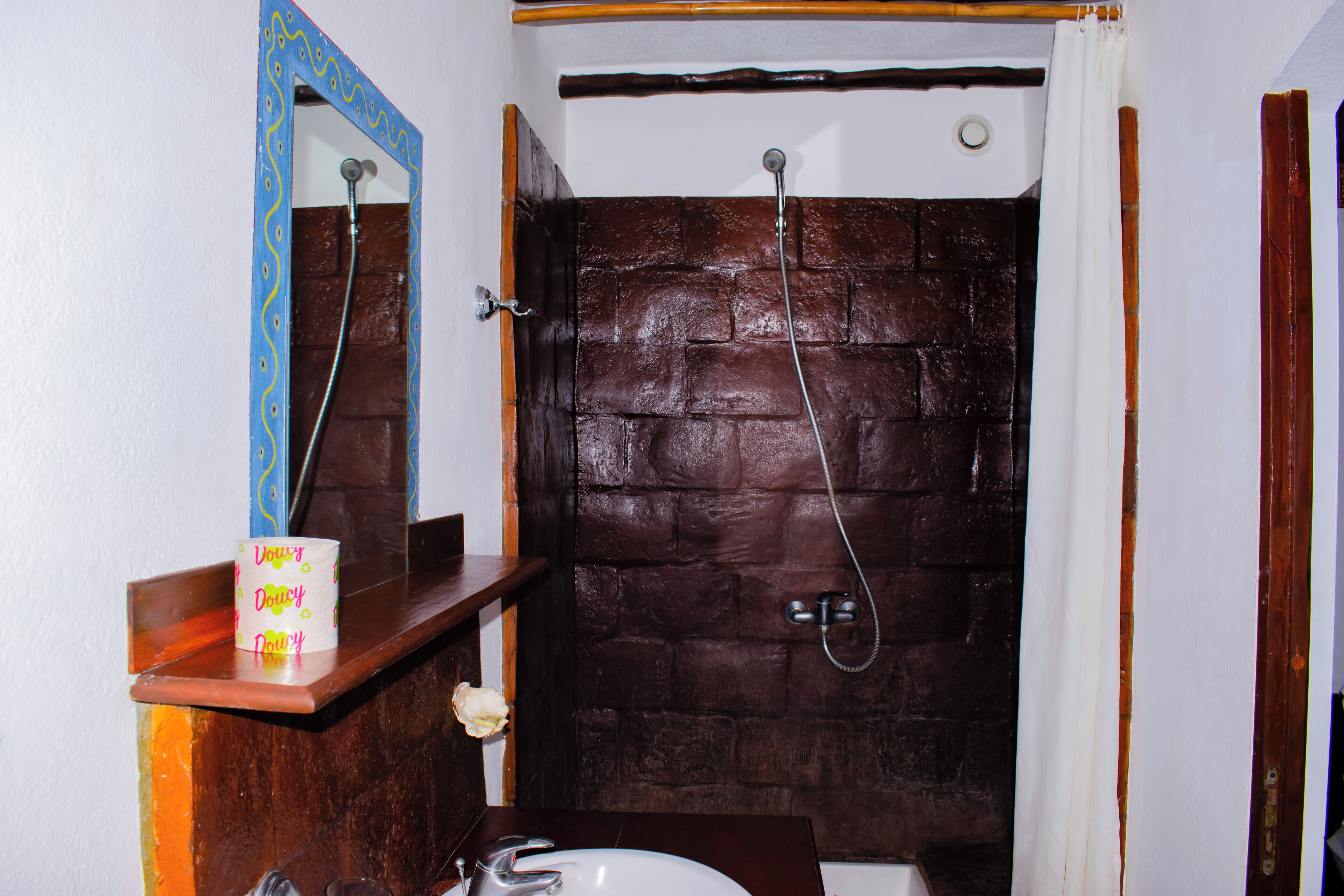 A bathroom with a wooden wall, a mirror, a sink, and a shower.