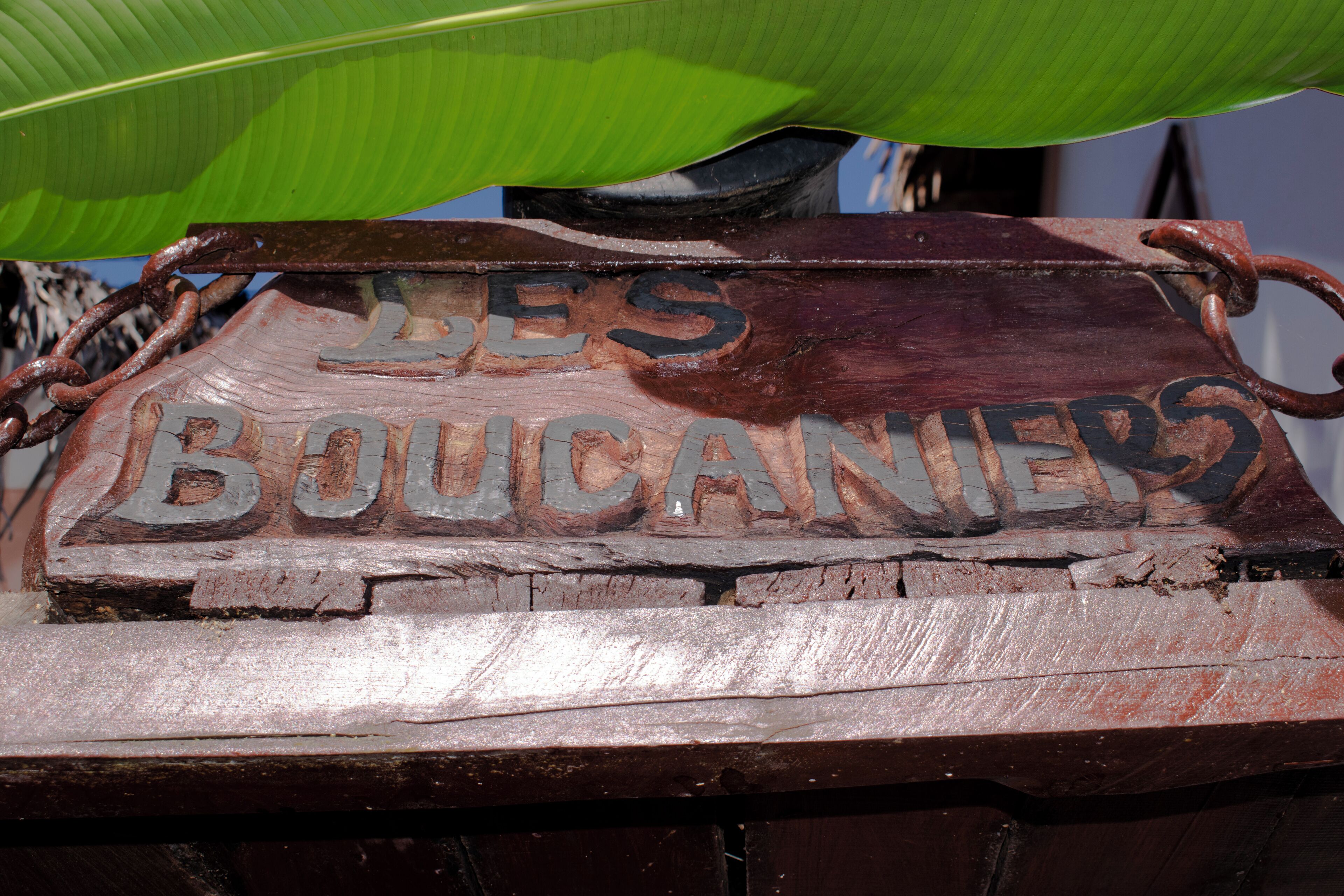 Une enseigne en bois rustique portant l’inscription « LES BOUCANIERS ».