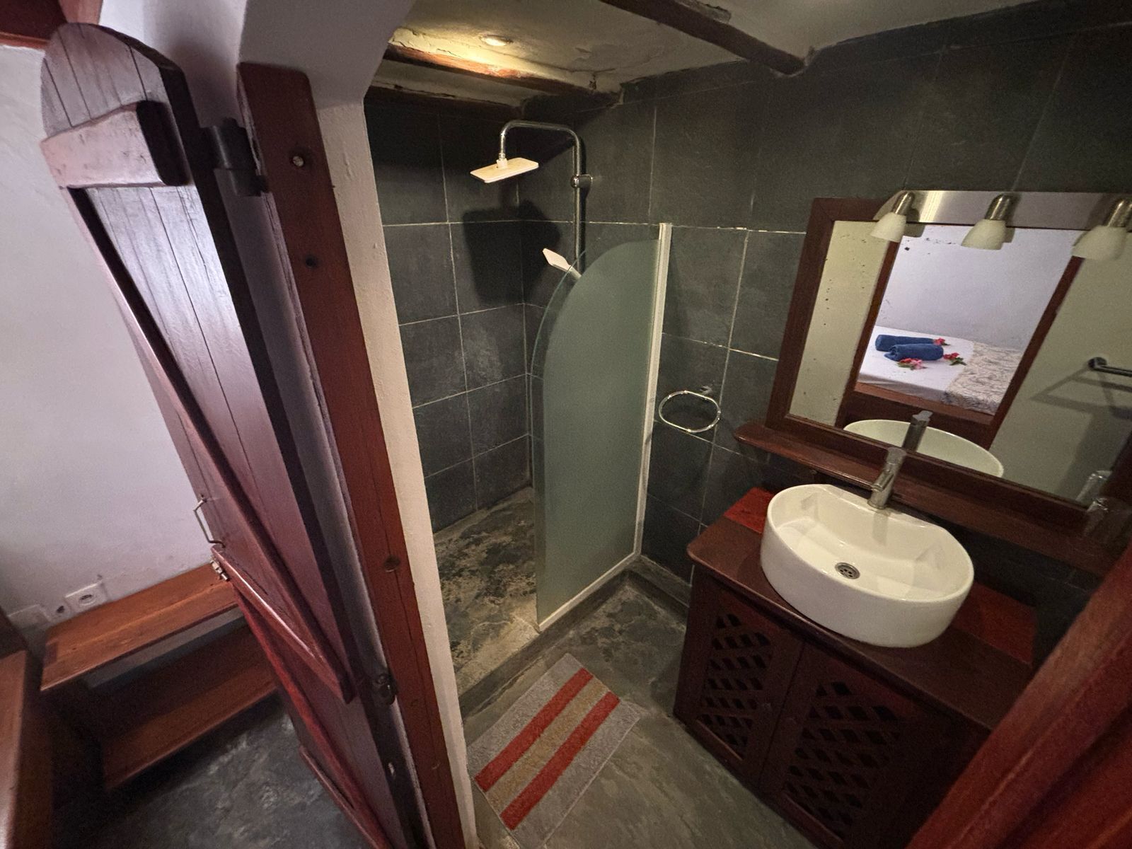 Un baño con cabina de ducha de vidrio, un lavabo y un espejo.