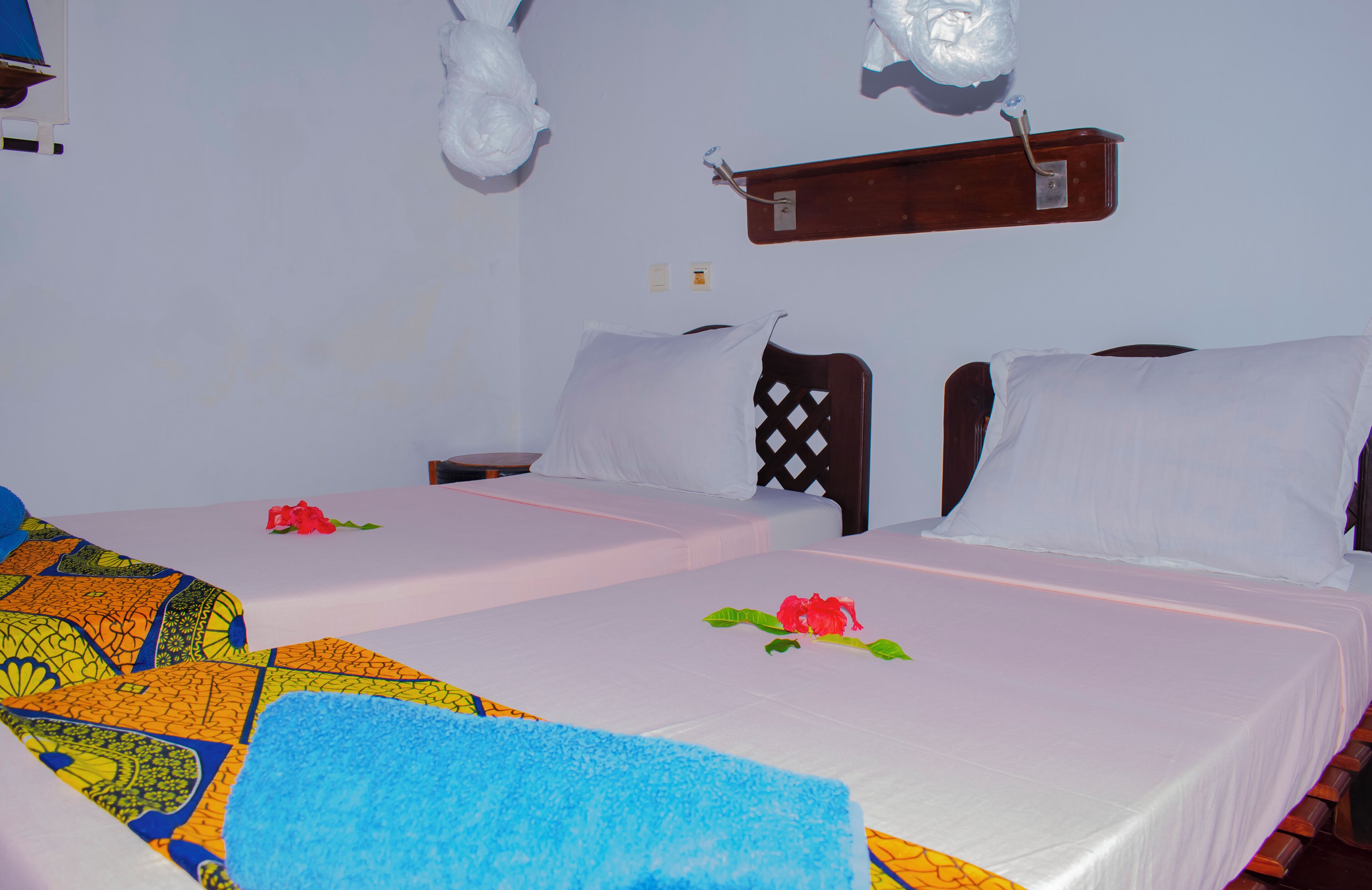 A hotel room with two beds, white bedding, and a colorful blanket.