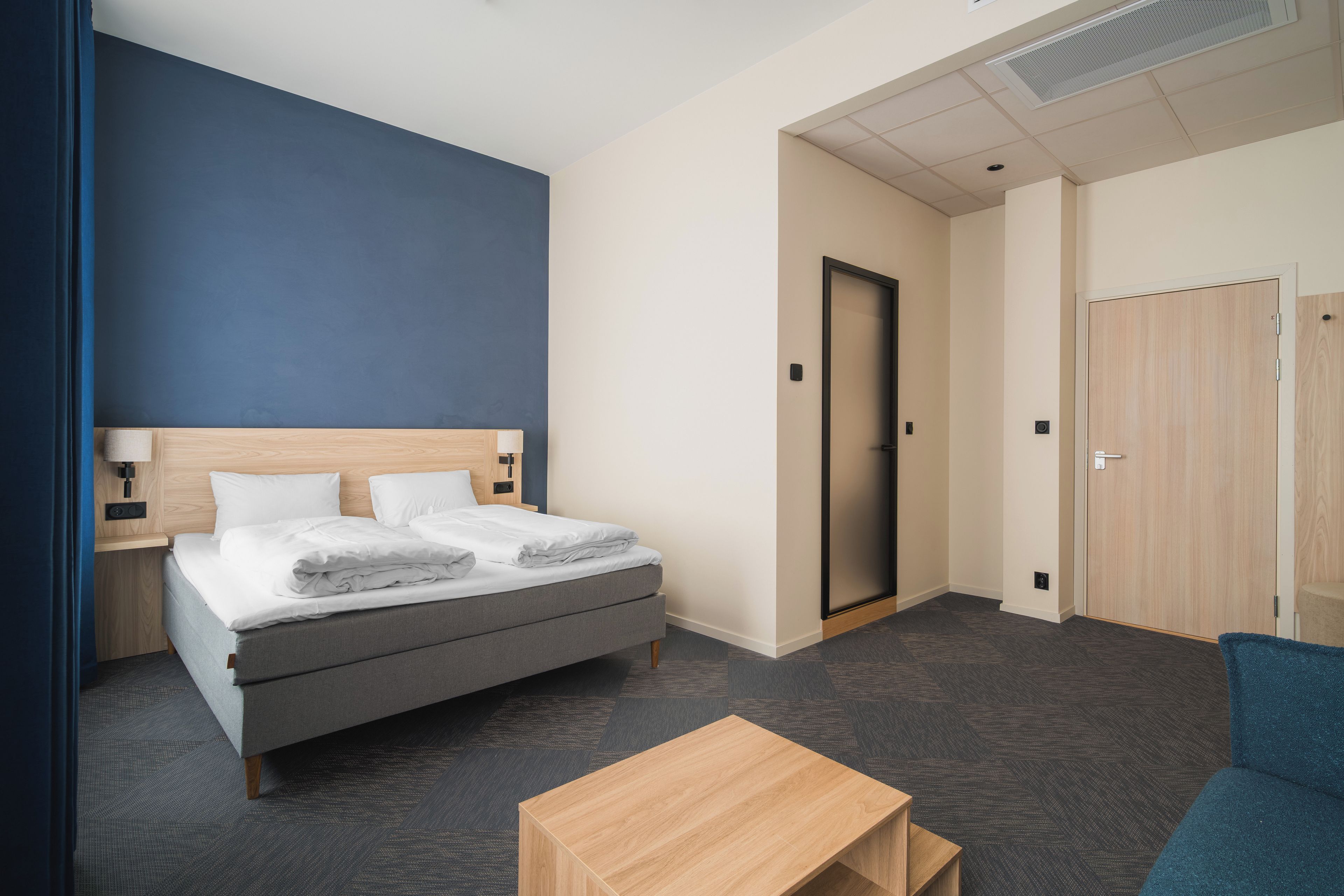 Een hotelkamer met een bed, een bureau, een stoel en een deur.