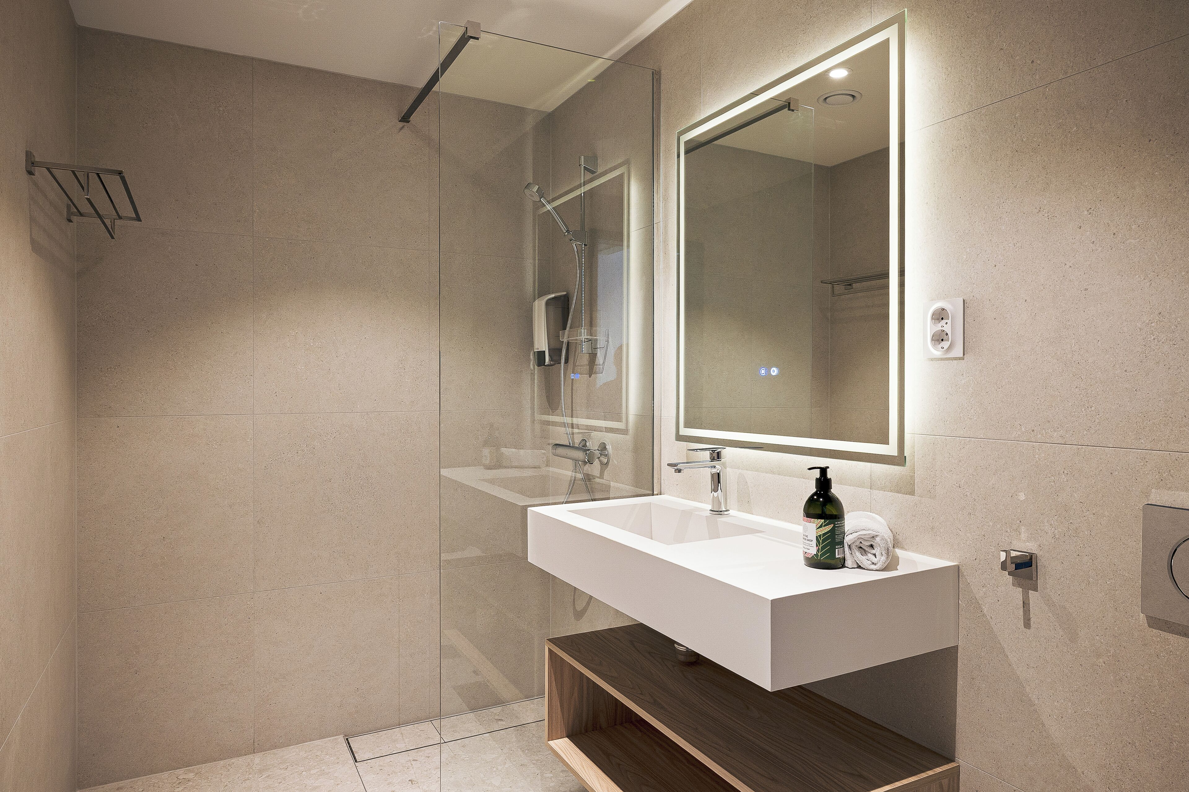 Ein modernes Badezimmer mit einer gläsernen Duschkabine, einem weißen Waschbecken und einem großen Spiegel.