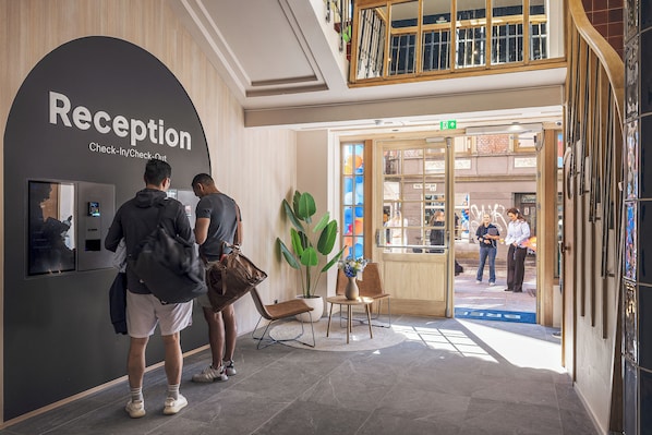 A reception area with a check-in/check-out counter, a plant, and a seating area. - BREEZE Bergen City - Self-Service (Bergen)