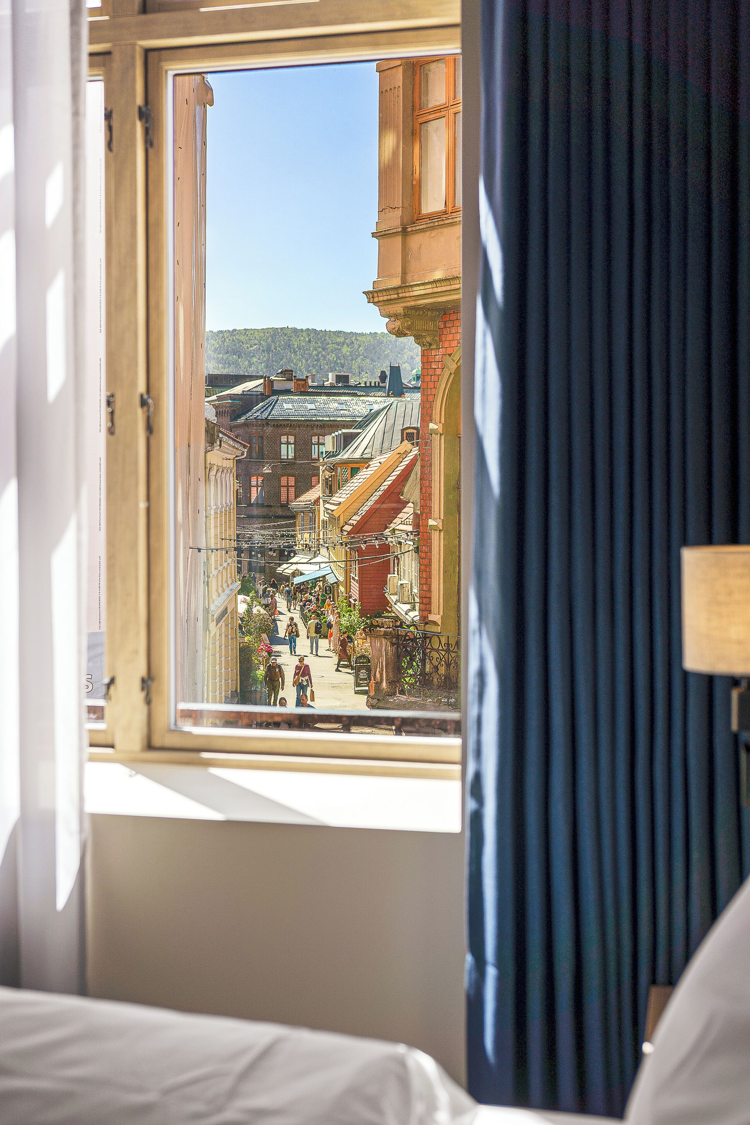 A hotel room with a view of a city street through an open window.