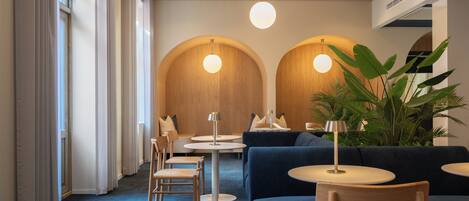 A modern interior with round tables, sofas, and a large plant.
