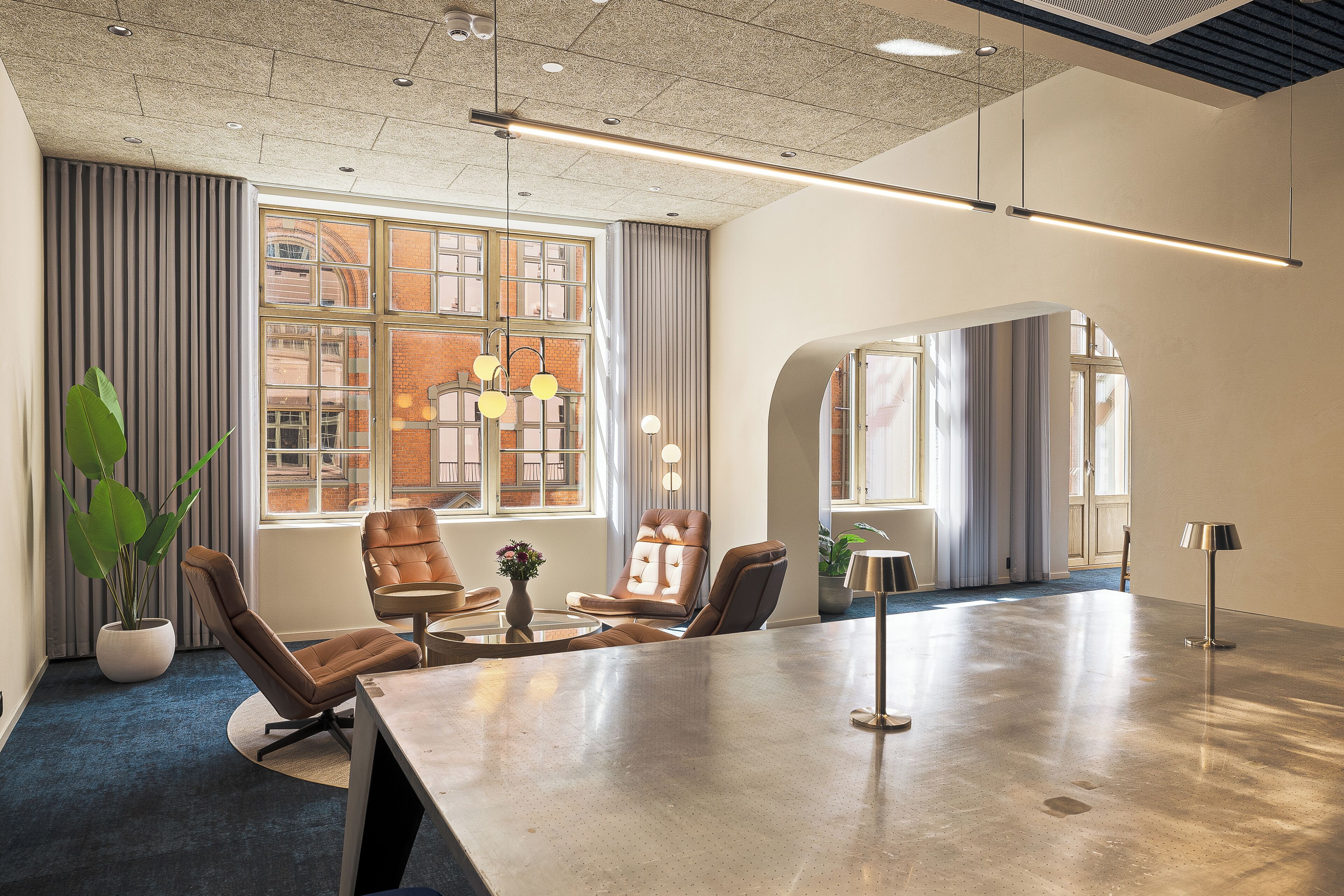 A modern conference room with a large table, leather chairs, and large windows with curtains.