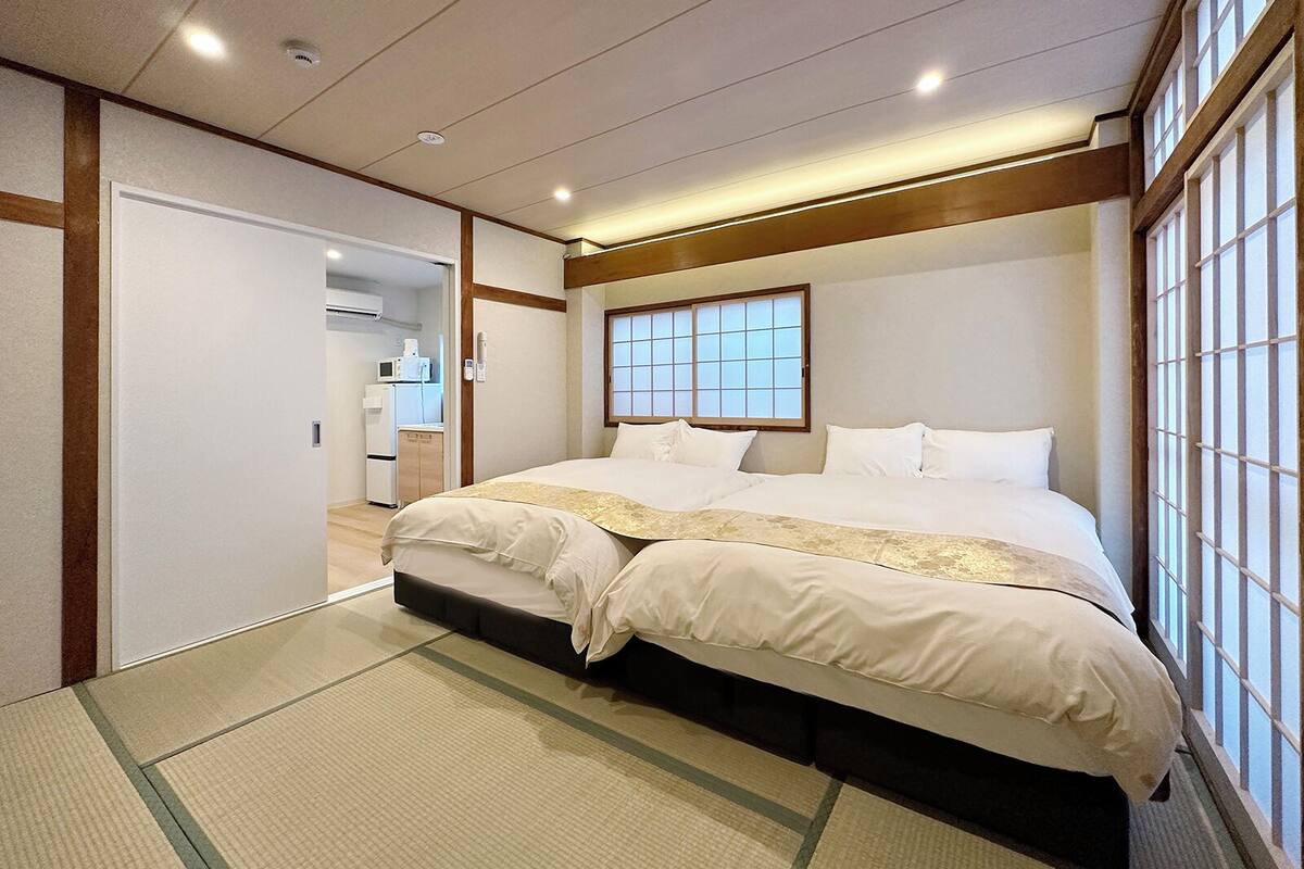 A hotel room with a bed, a window, and a kitchenette.
