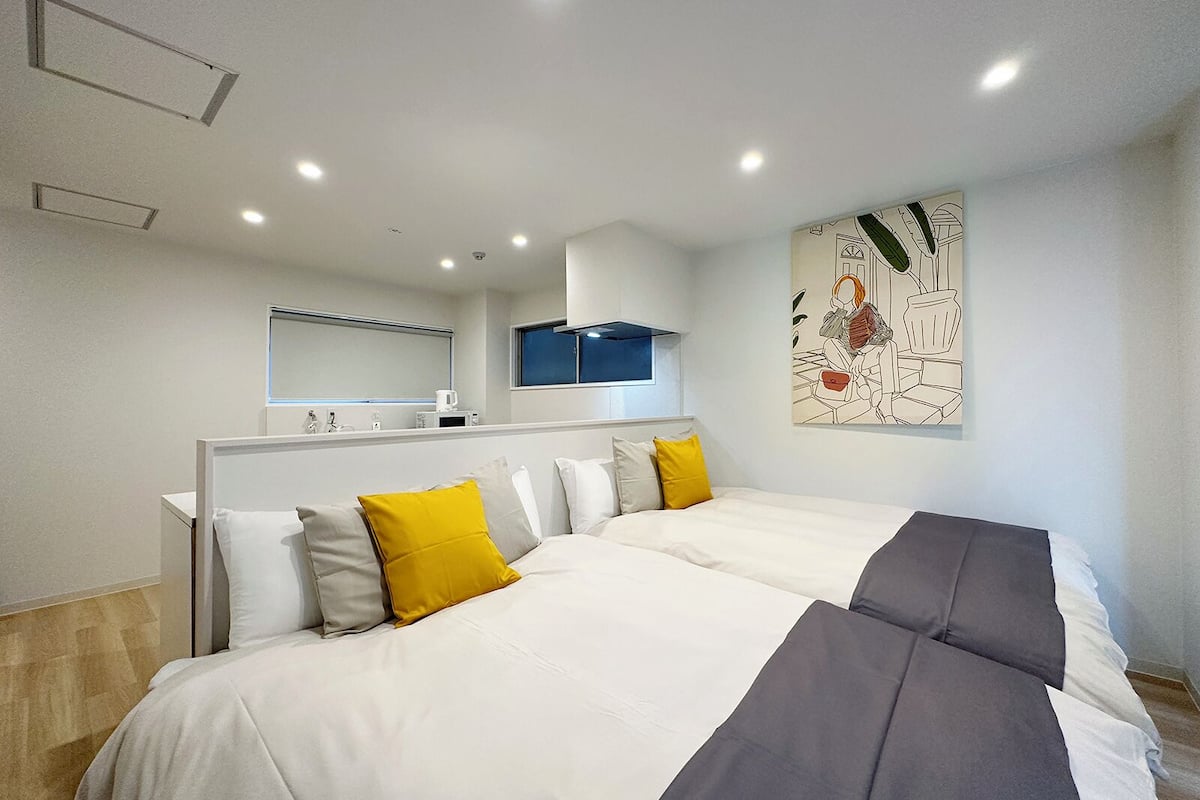 A modern hotel room with a large bed, a bedside table, a mirror, and a wall-mounted artwork.