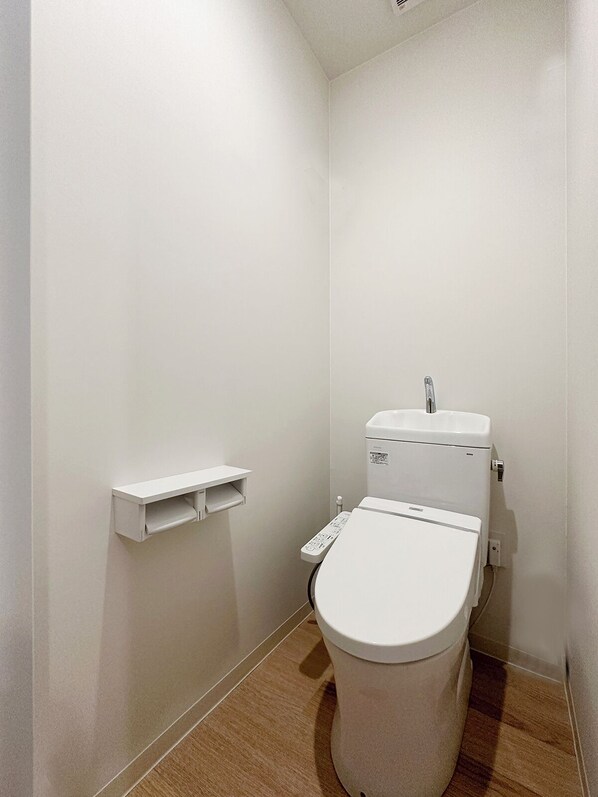 Une petite salle de bain propre, équipée de toilettes, d’une étagère et d’un panneau de commande.