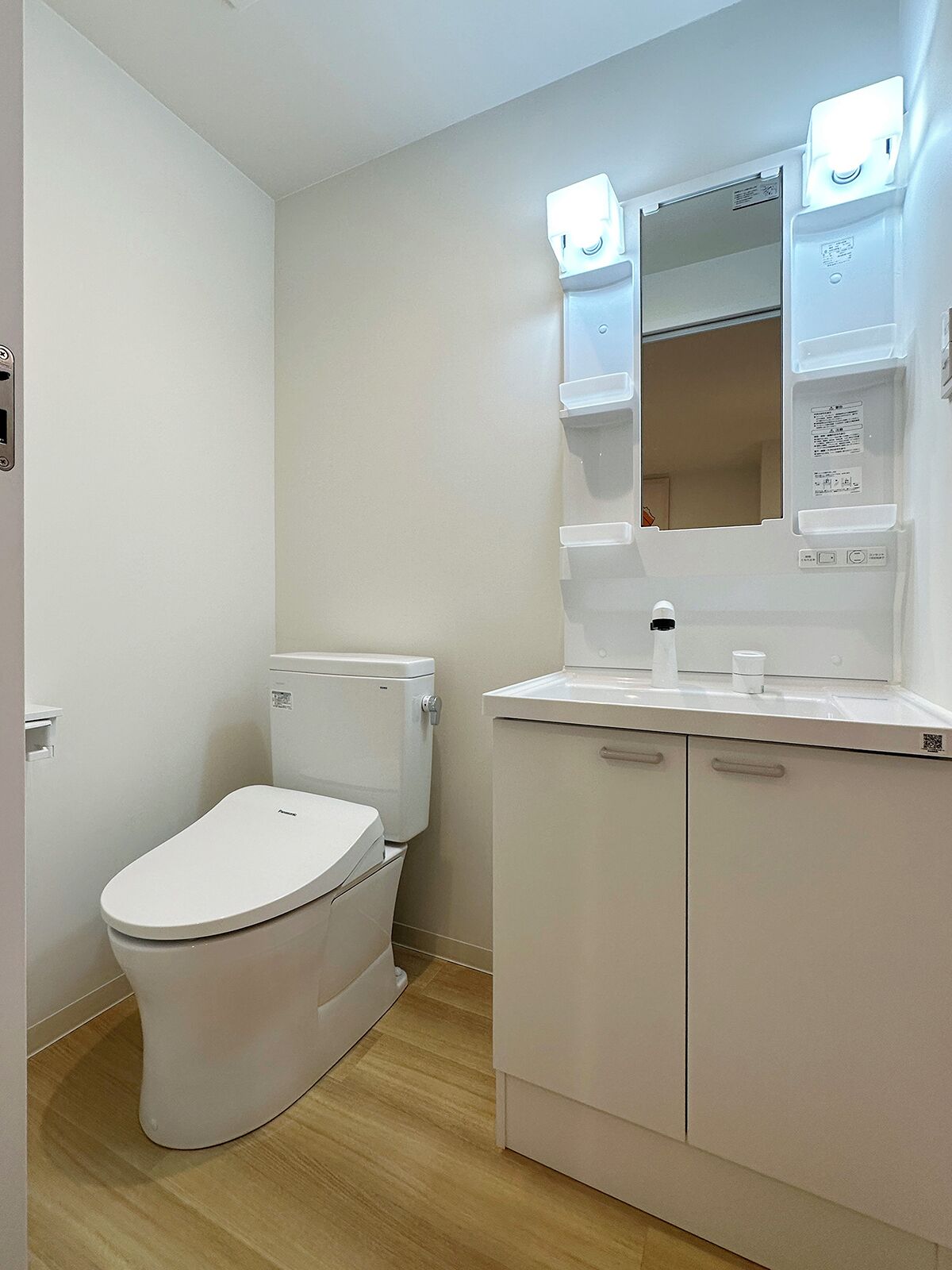 A modern bathroom with a white toilet, a sink with a mirror, and a cabinet.