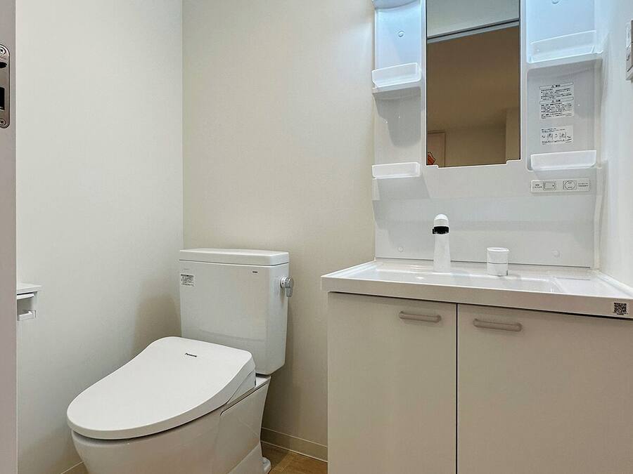 A modern bathroom with a white toilet, a sink with a mirror, and a cabinet.