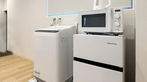 Een schone, moderne kamer met een Hisense magnetron en koelkast, houten vloeren en een effen witte wand.