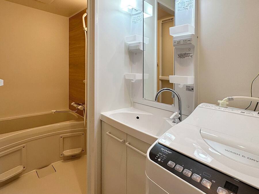 Un baño moderno con ducha a ras de suelo, lavabo empotrado y lavadora blanca.