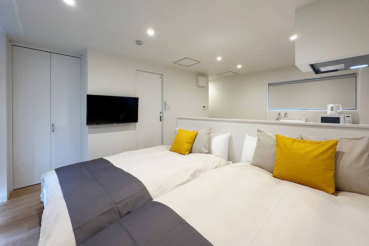A hotel room with two beds, a TV, a microwave, and a mirror.