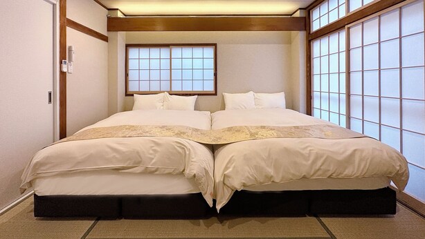 Een traditionele Japanse slaapkamer met een tweepersoonsbed, schuivende shoji deuren en een klein raam.