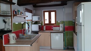 A compact kitchen with wooden cabinets, a microwave, a toaster, and a refrigerator.