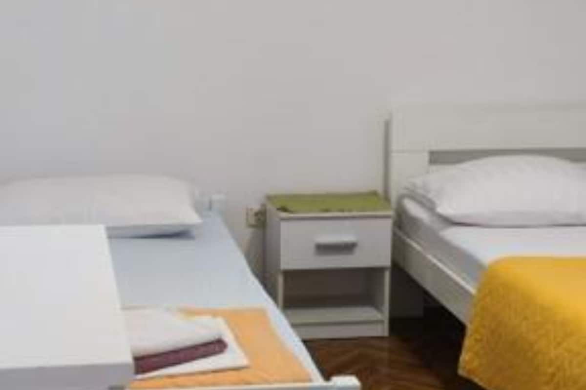 A small, clean room with two single beds, a bedside table, and a nightstand.