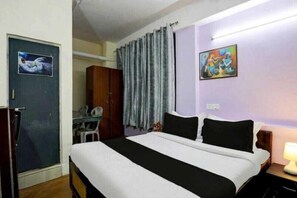 Ein Schlafzimmer mit Bett, Schreibtisch, Kleiderschrank und einer Tür mit einem Bild.