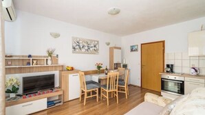 A compact hotel room with a kitchenette, a dining area, and a bed.