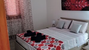 Ein ordentlich bezogenes Bett mit einem gemusterten Bettüberwurf, einem an der Wand befestigten Kunstwerk und einem Nachttisch mit Lampe.