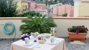 Ein Tisch auf einem Balkon mit Blick auf ein Wohngebiet, ein Gartenschlauch und ein Blumentopf.