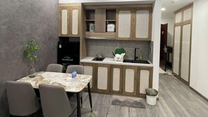 Een moderne keuken met houten kastjes, een eettafel met stoelen en een klein aanrecht met een spoelbak.