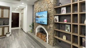 Een moderne woonkamer met een stenen openhaard, een bevestigde televisie en ingebouwde houten planken.