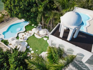 Relax by the wavy pool surrounded by lush greenery and palm trees.