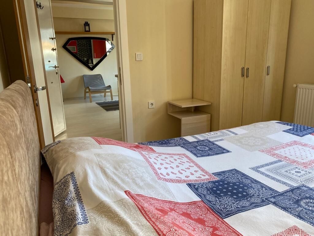 A bedroom with a bed, a wardrobe, a chair, and a small table.