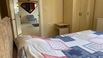 A bedroom with a bed, a wardrobe, a chair, and a small table.