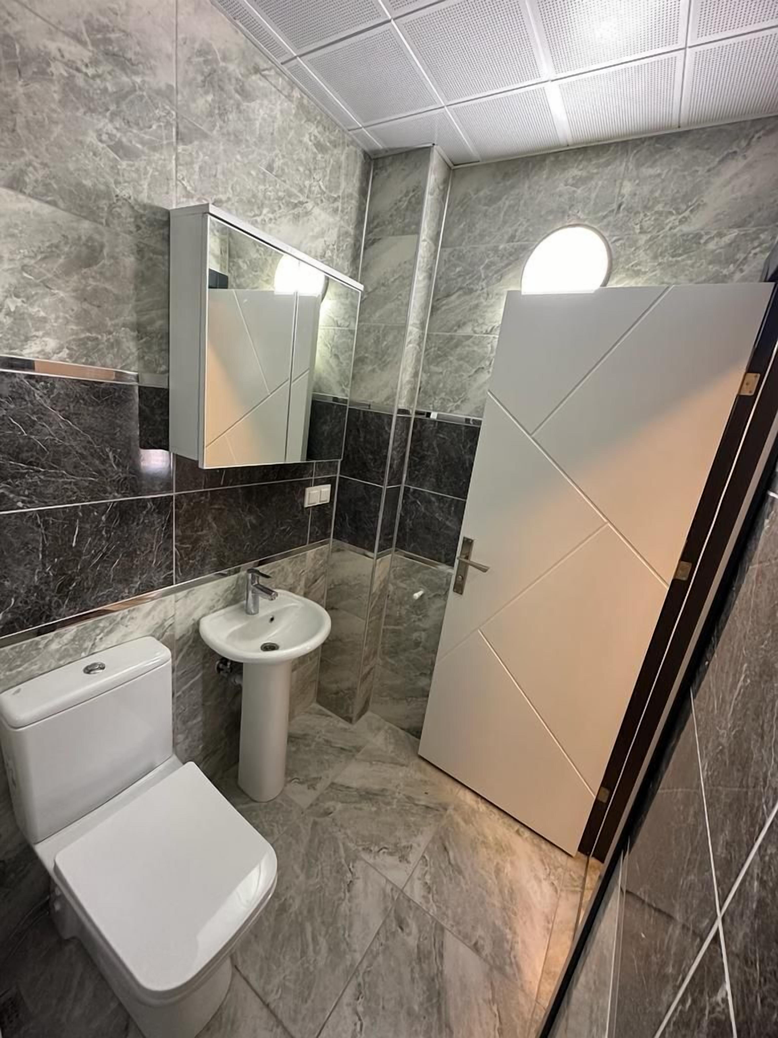 Un baño moderno con inodoro, lavamanos y zona de ducha.