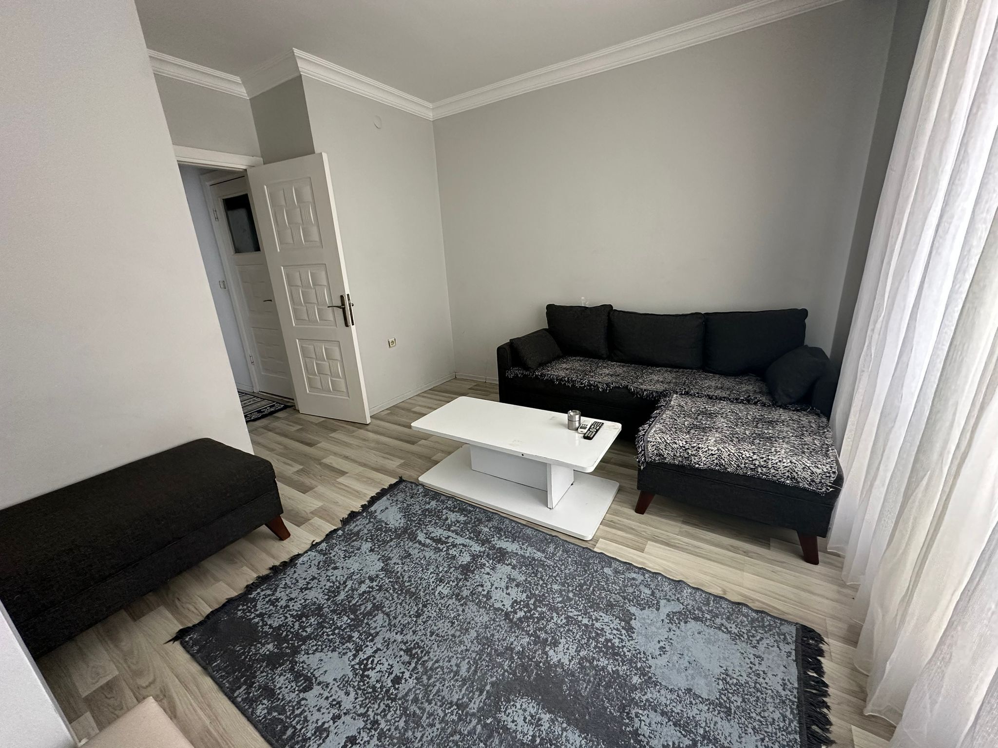 A living room with a white coffee table, a black sofa, and a black ottoman.