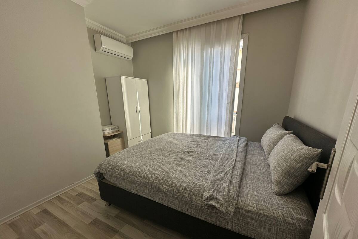 A bedroom with a bed, a wardrobe, and an air conditioning unit.