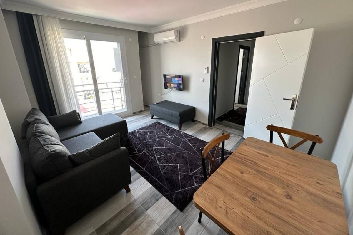 A modern living room with a sofa, a wooden table, and a TV mounted on the wall.