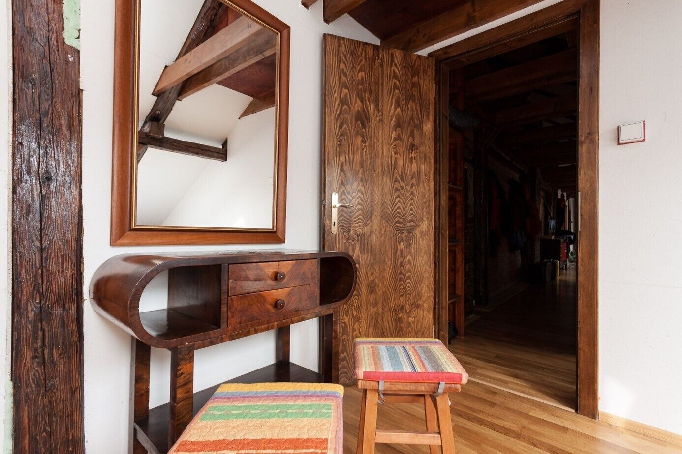 Una habitación con un escritorio de madera, un espejo y un tapete colorido.