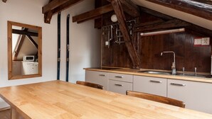 A kitchen with wooden beams, a wooden table, and a sink.
