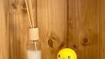 Una repisa de madera con una botella de vidrio y un patito de goma.