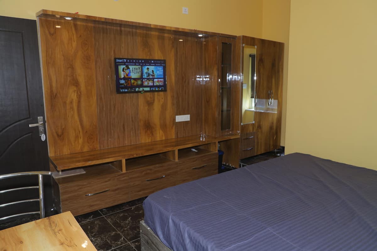 Um quarto com um guarda-roupa de madeira, uma cama com colcha azul e uma pequena mesa.