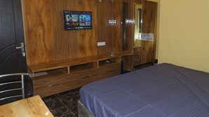 Une chambre avec une armoire en bois, un lit recouvert d’une couverture bleue et une petite table.
