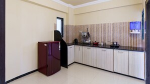 A kitchen with a refrigerator, a water dispenser, and a coffee machine. - Lazy Daze By Unique Choice Hotels (Udaipur)