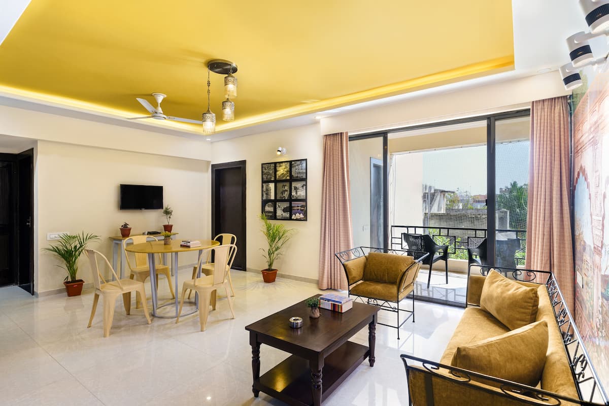 A modern living room with a dining area, a sofa, and a balcony with a view.