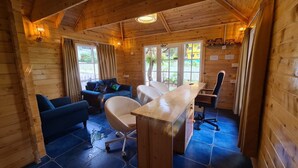 A wooden cabin with a dining area, a sofa, and a chair. - Aranya Abode (Arambol)